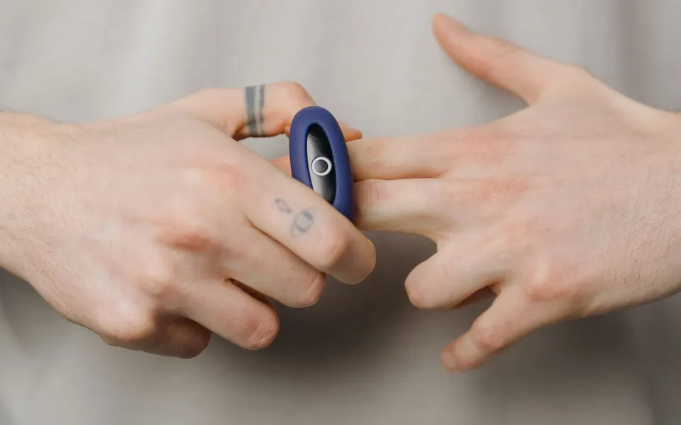 Bague anti stress en acier inoxydable portée sur un doigt, gros plan lumineux sur fond neutre